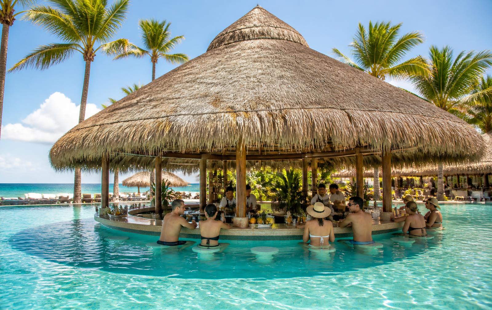 All-inclusive resort swim-up bar with guests in the pool