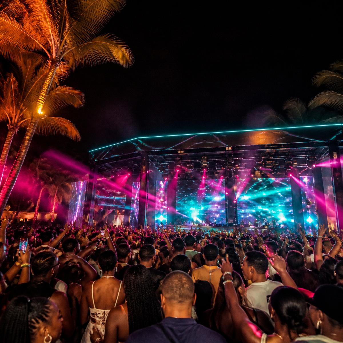 Festival crowd with hands up in front of a lit outdoor stage